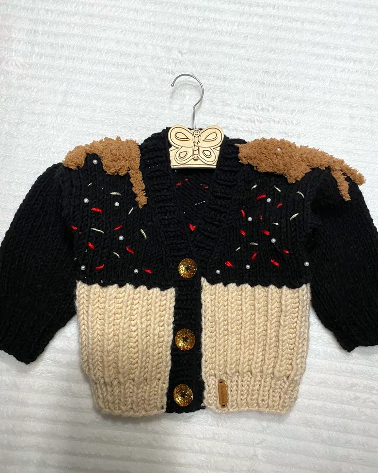 Gestrickte Kinderjacke in Schwarz und Beige mit bunten Streuseln