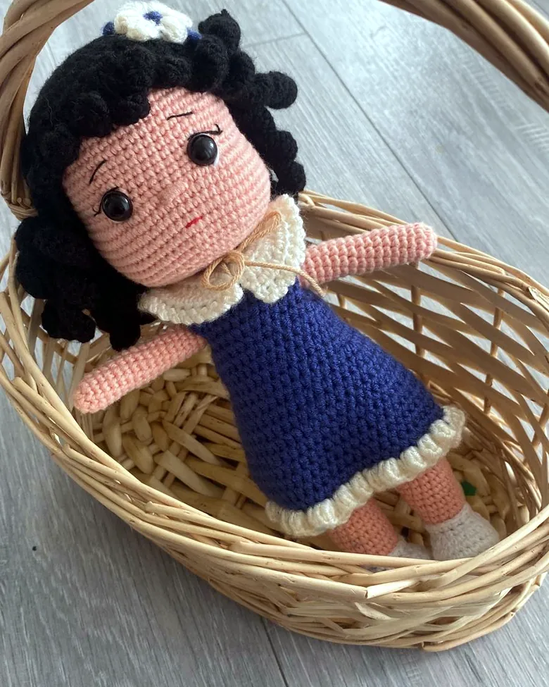 Gehäkelte Puppe mit blauem Kleid im Korb